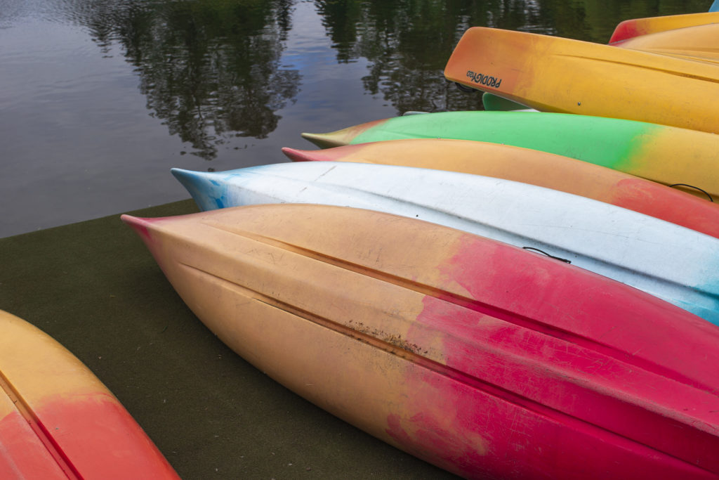 Colorful canoes laying on a shore of green lake
